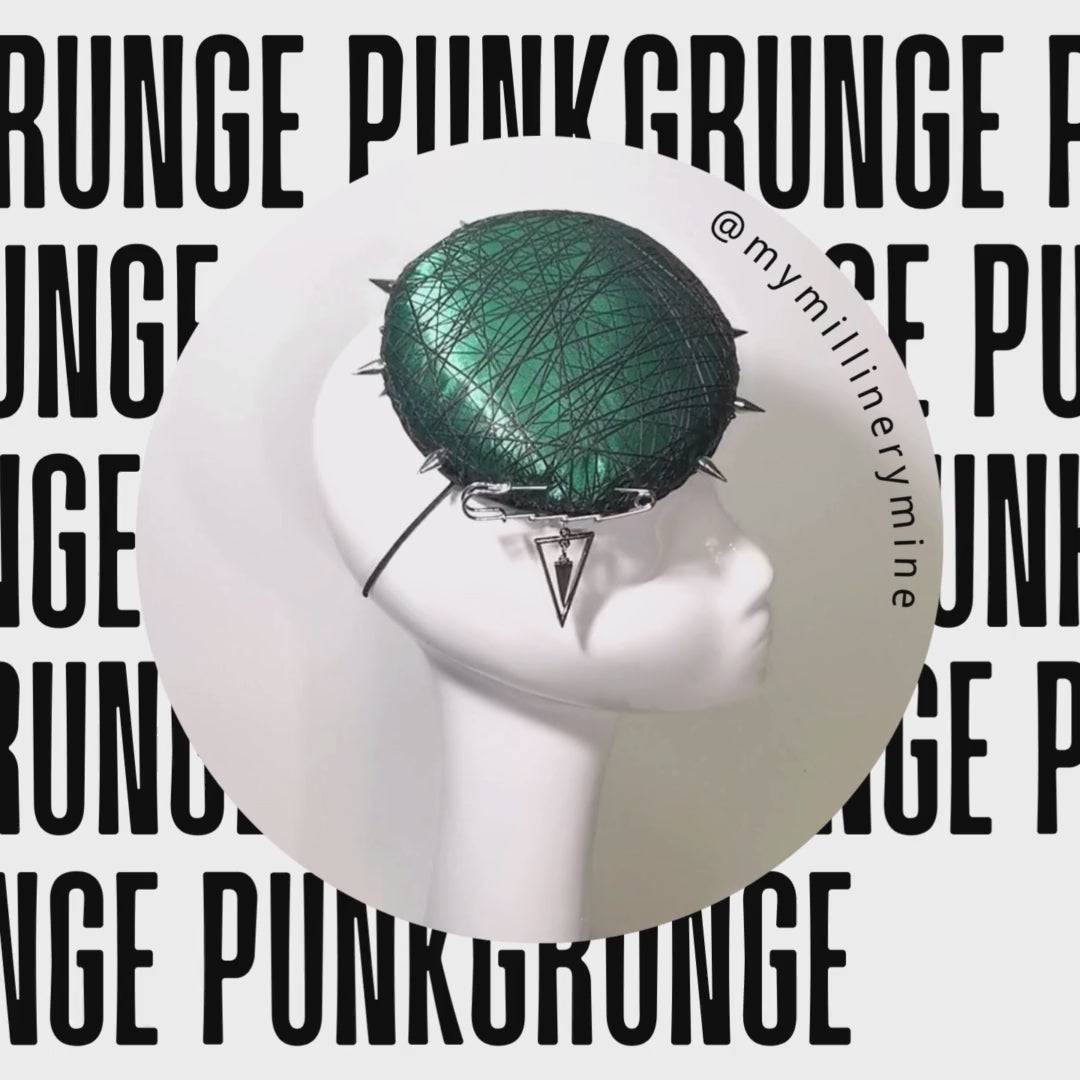 A Grunge-punk Emerald Green Cocktail Hat with punk screw metal rivets is displaying on a rotating mannequin 